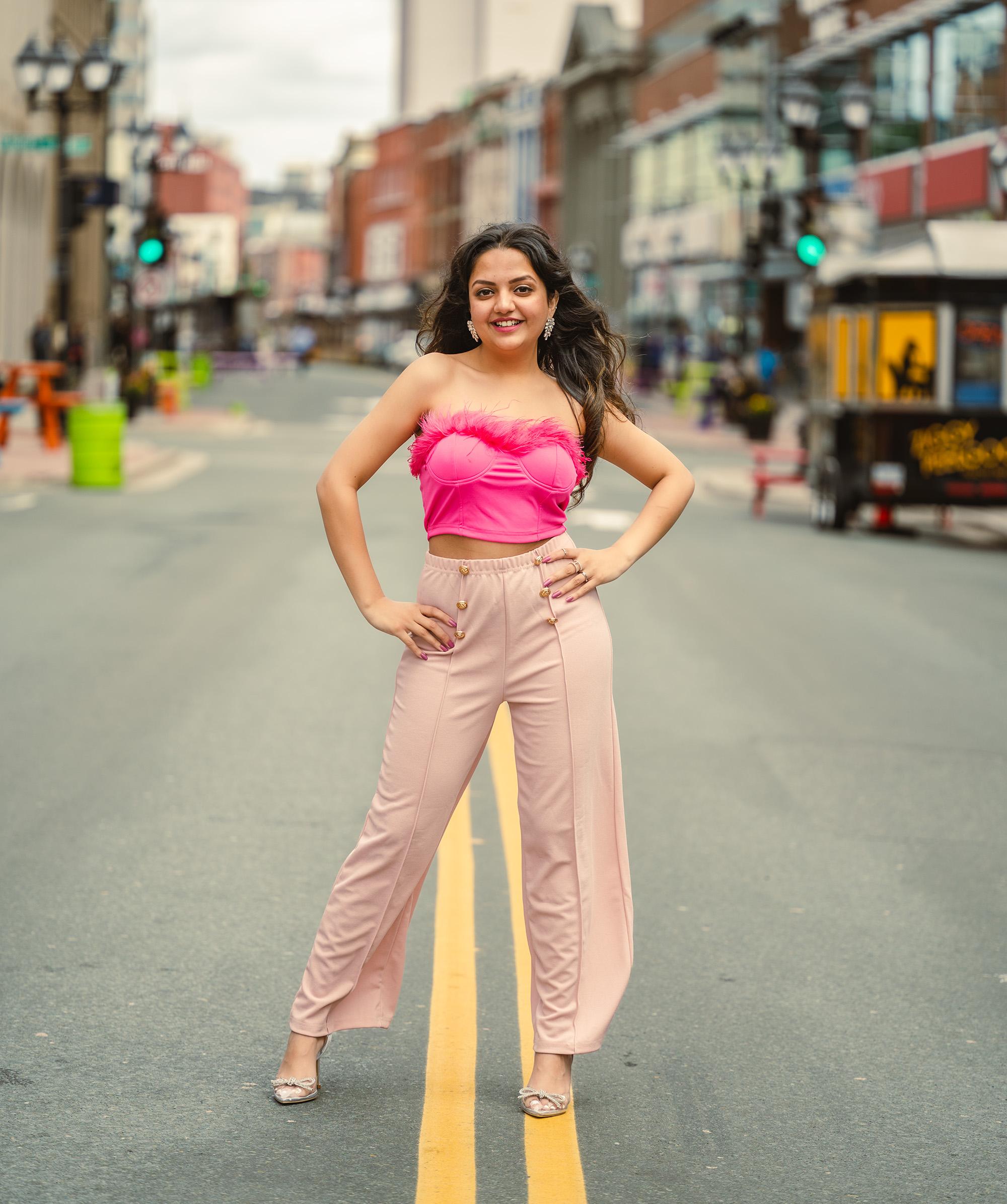 A woman stands confidently in the street in St. John's, Newfoundland, wearing a pink outfit